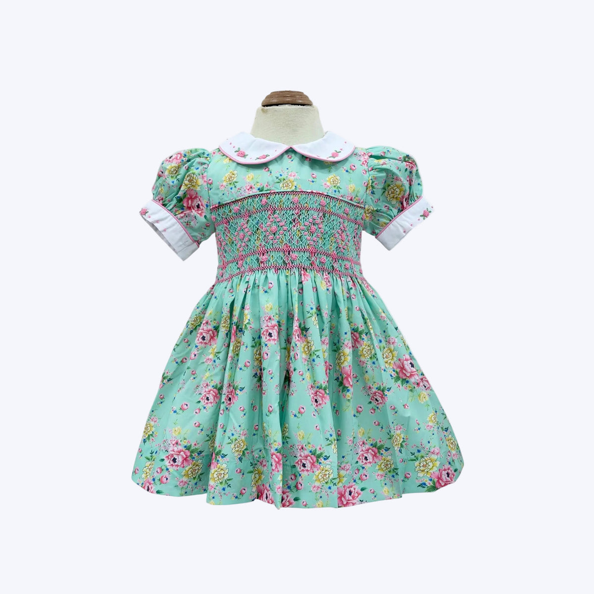 Mannequin front view of girls hand-smocked vintage floral dress in mint green