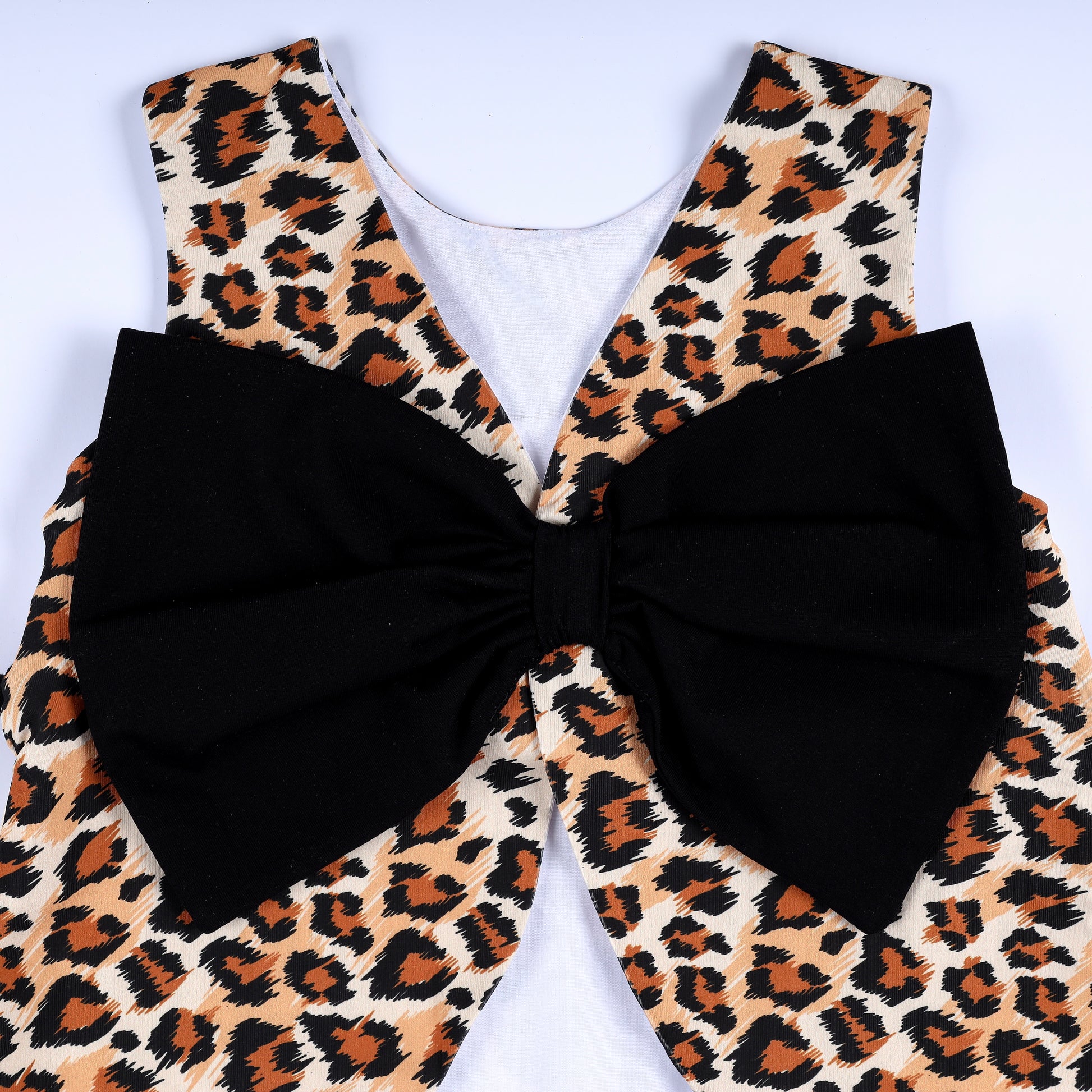 Close-up view of the oversized black statement back bow on the girls leopard print safari smocked top.