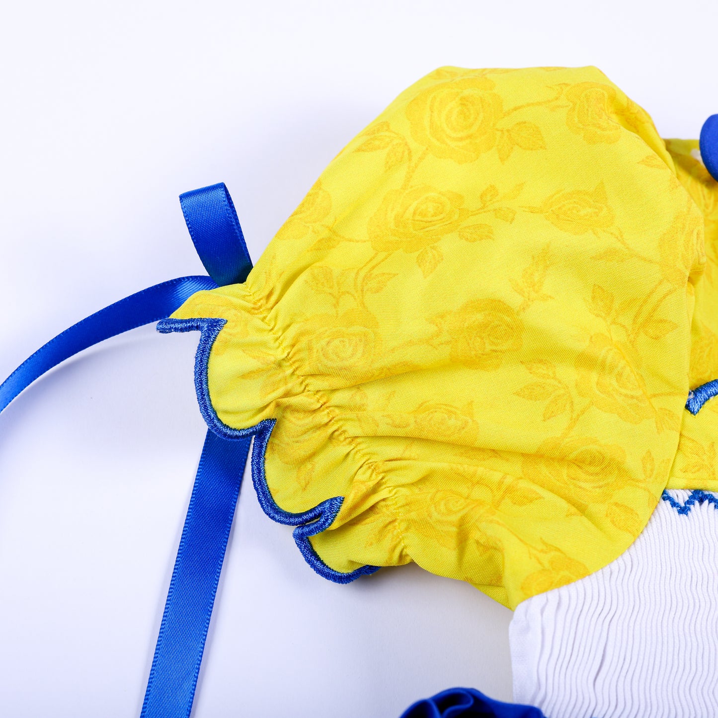 Yellow rose print puff sleeve featuring scalloped blue embroidered edging and royal blue ribbon tie detail.