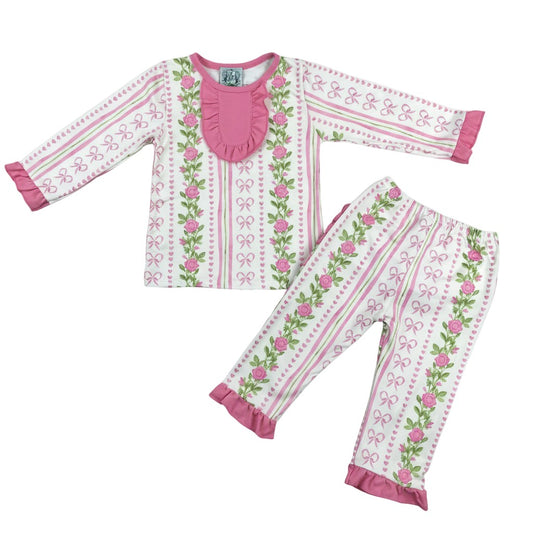 Flat lay view of girls grandmillennial floral pink hearts pajama set with long sleeve ruffled top and stripe pants.