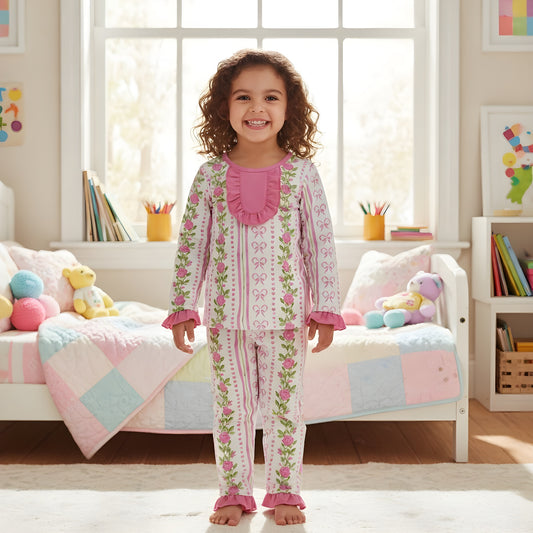 Front view of a toddler girl wearing the grandmillennial floral pink hearts pajama set with ruffled collar and cuffs.