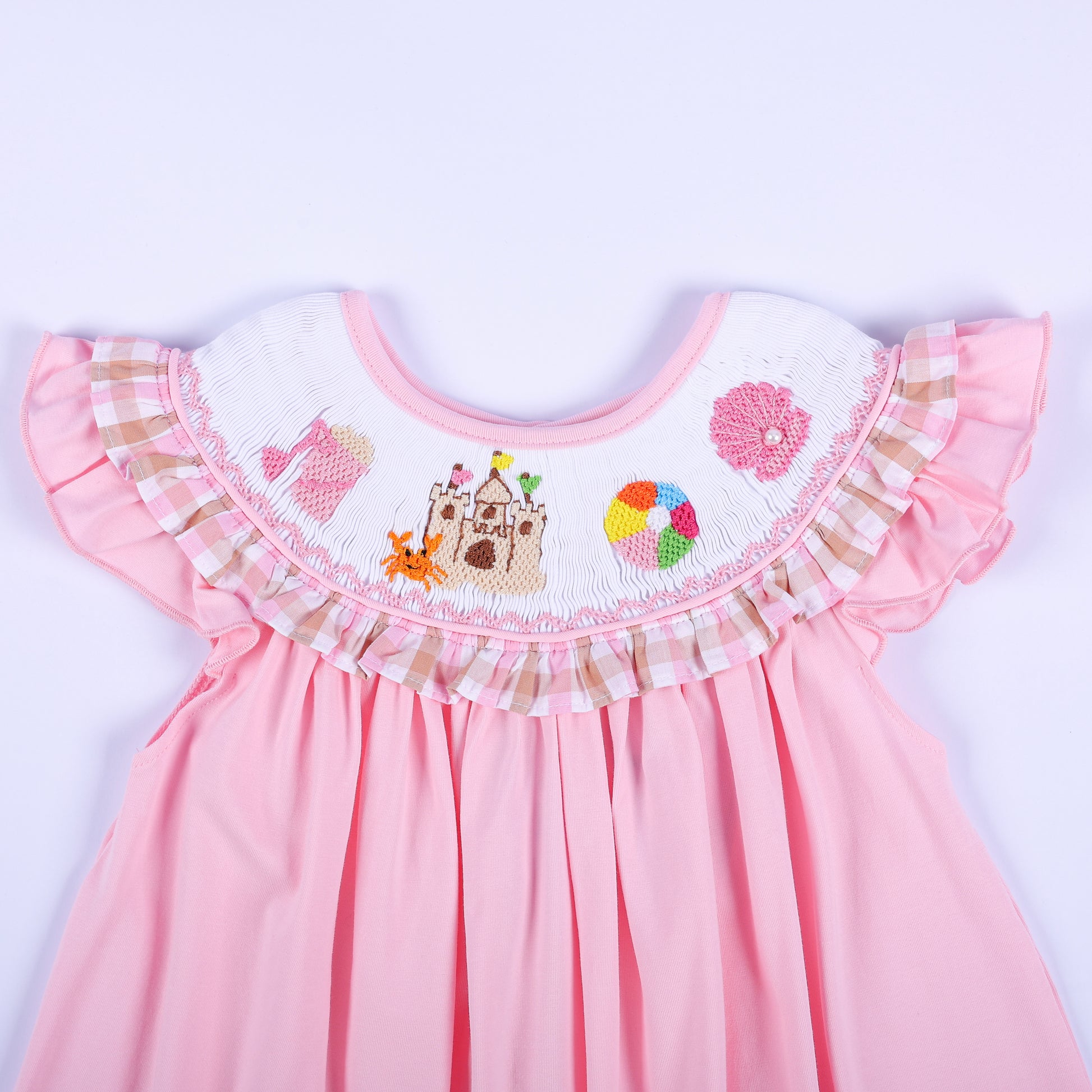 Close-up of hand embroidered beach collar with sandcastle, crab, beach ball, and pink shell on smocked dress.
