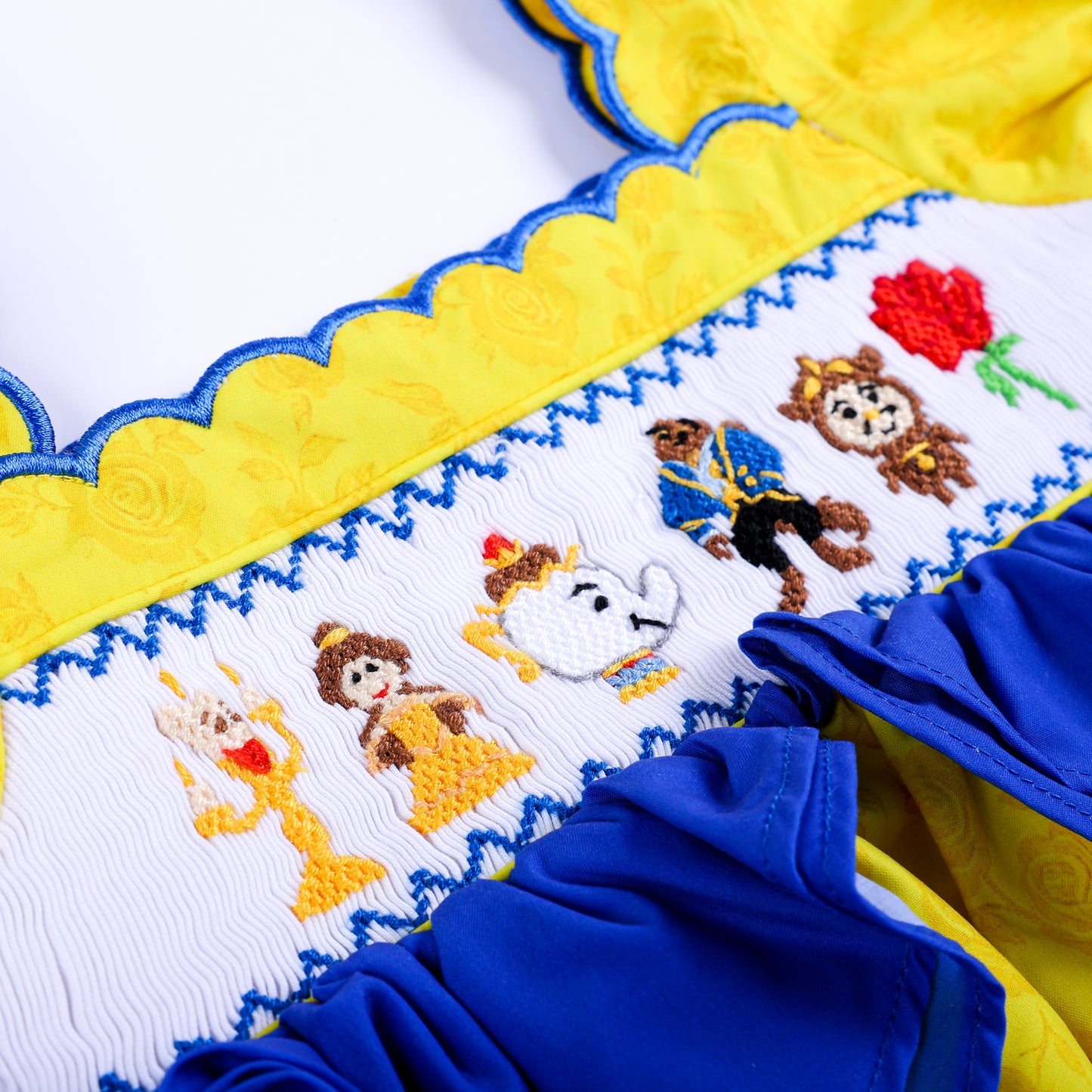 Intricate hand-embroidered Belle, Beast, Lumiere, Mrs Potts, and rose design on girls smocked white bodice.