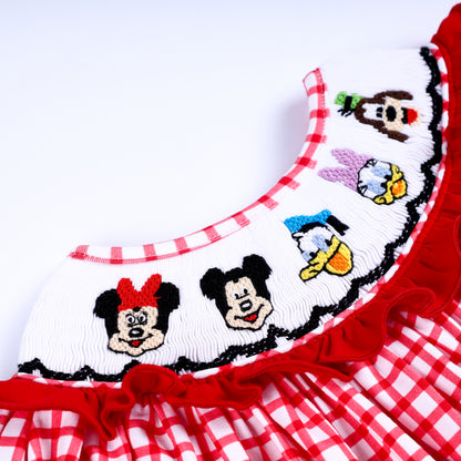 Detailed view of hand-embroidered cartoon character faces on the smocked collar of a red gingham baby bubble outfit.