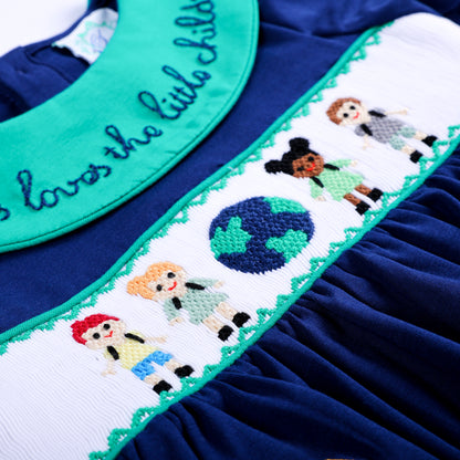 Close-up of hand smocked waist plate featuring embroidered children holding hands around the world on navy fabric.