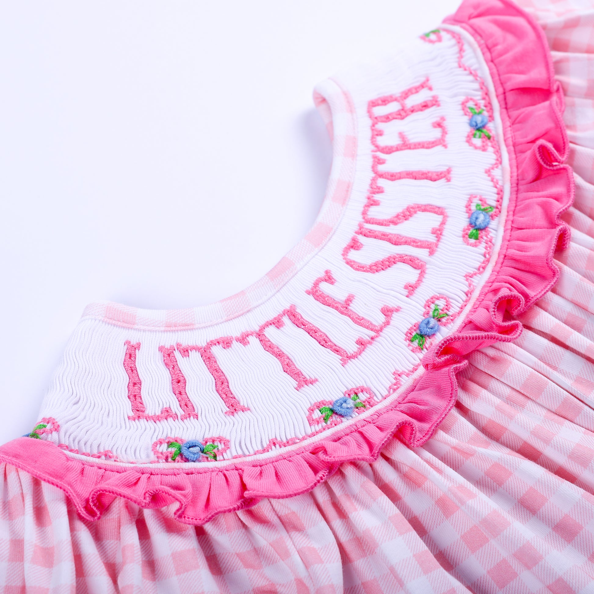 Macro close up of hand embroidered Little Sister text and floral details on smocked pink gingham bubble collar.