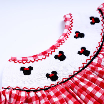 Close-up of hand embroidered black mouse motifs on the white smocked collar of a girls red gingham dress.