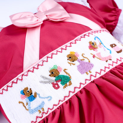Close up of hand embroidered sewing mice scene on white smocked plate of pink hand smocked girls dress.