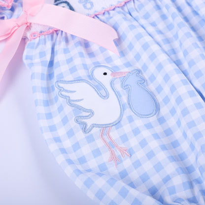 Detailed close-up of the hand-embroidered stork delivery motif on the light blue gingham gender reveal bubble romper.