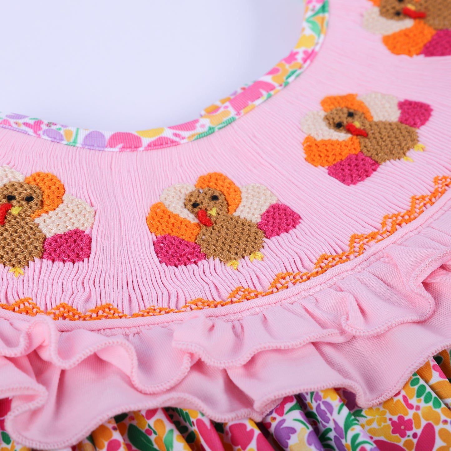Detailed view of the hand-embroidered turkey design and pink smocked neckline on the Thanksgiving boutique outfit.
