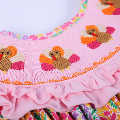 Detailed view of the hand-embroidered turkey design and pink smocked neckline on the Thanksgiving boutique outfit.