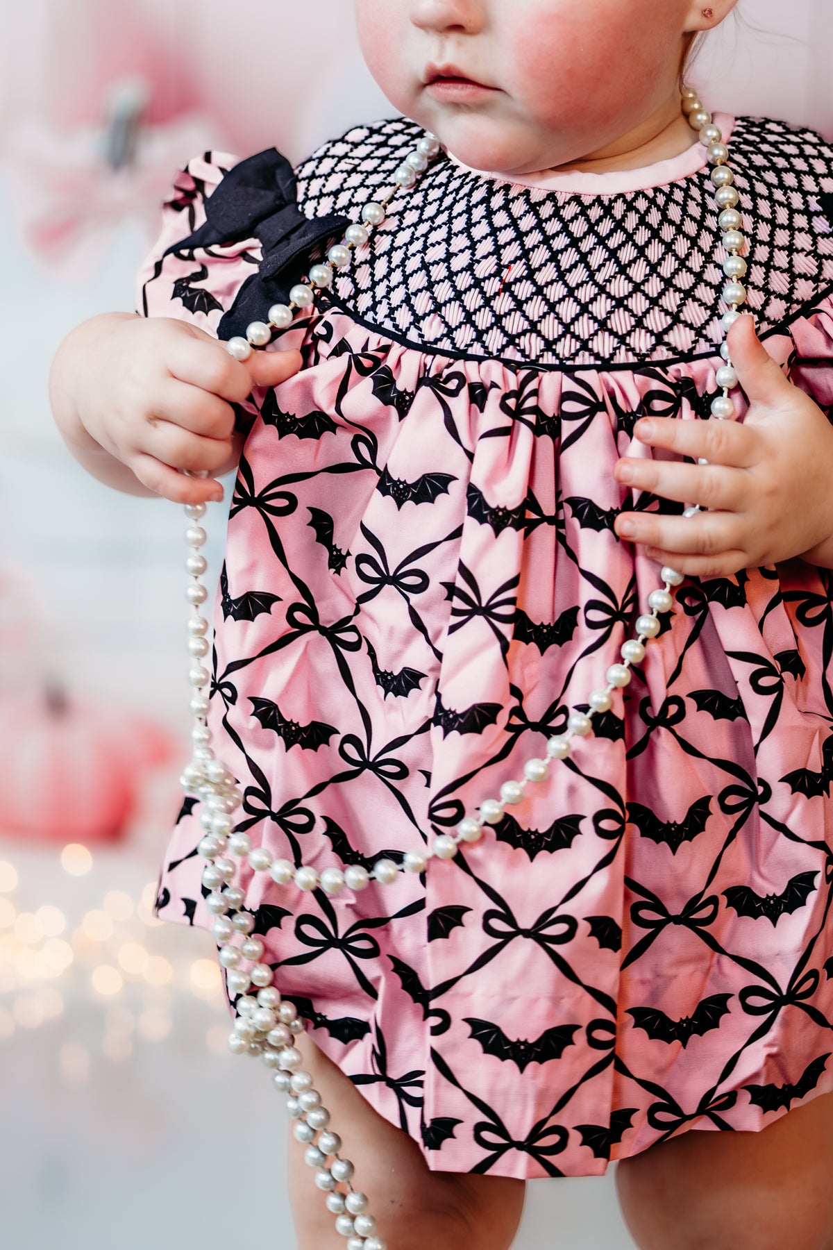 Close up of hand smocked bodice detail on Batty for Bows embroidered pink and black Halloween baby bloomer set.