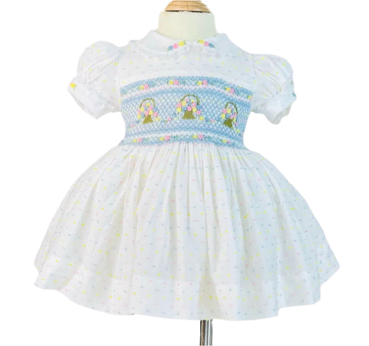 Blue hand smocked dress with hand embroidered flower baskets on white dotted fabric.