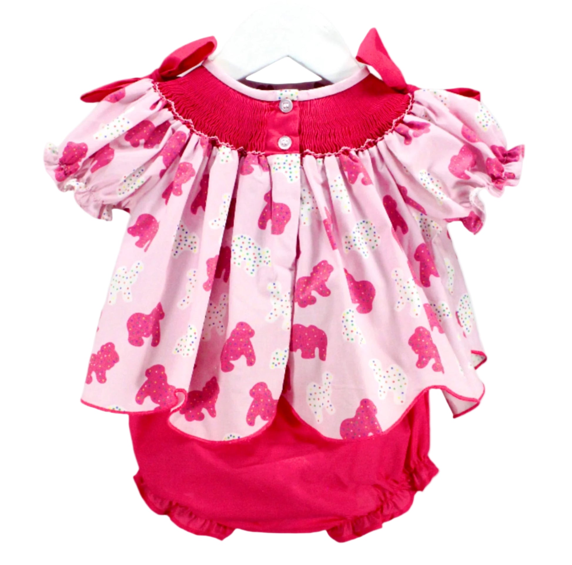 view of hand smocked frosted sprinkle animal cookies set top with button closure detail and pink ruffle bloomers.