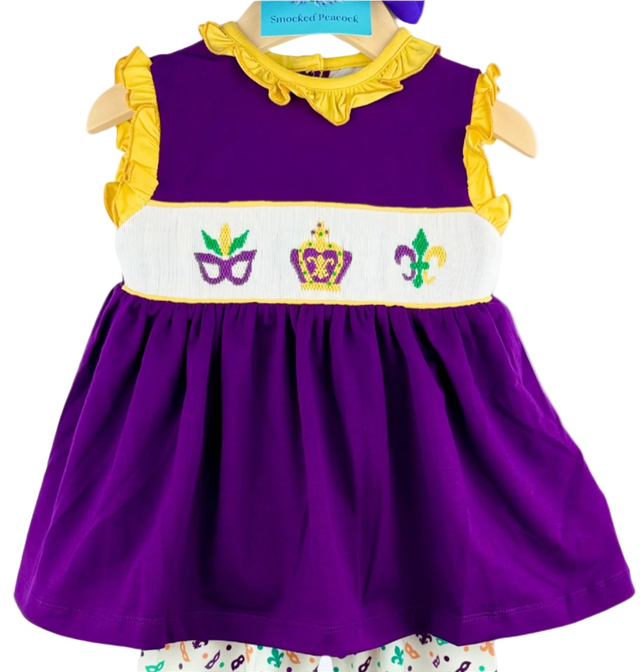 Hand-smocked Mardi Gras purple top with yellow ruffles and stitched mask, crown, and fleur-de-lis design.