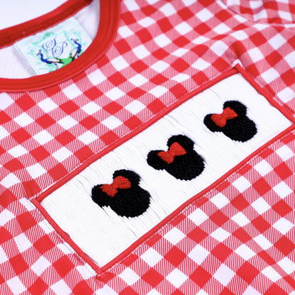 Detailed macro view of hand embroidered Minnie Mouse icons on white hand smocked chest plate of red gingham swimsuit.