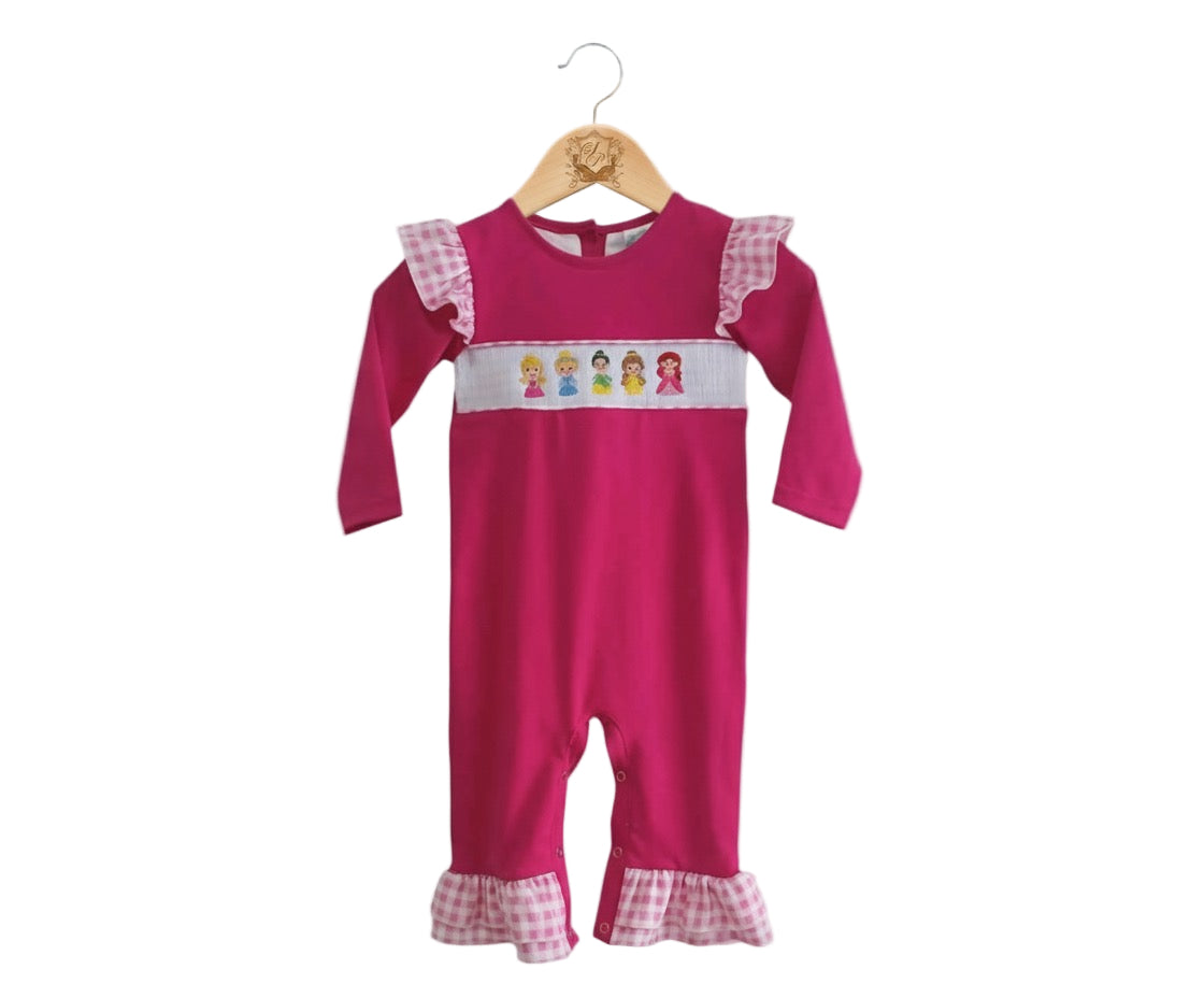 Front view of hand smocked pink princess girl romper with embroidered princess detail and gingham ruffles.