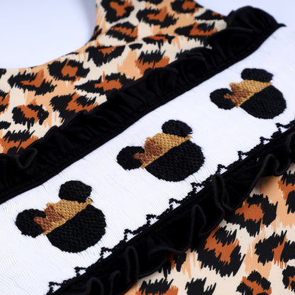 Detailed close-up of hand embroidered safari mouse heads and smocked bodice with black ruffle accents.