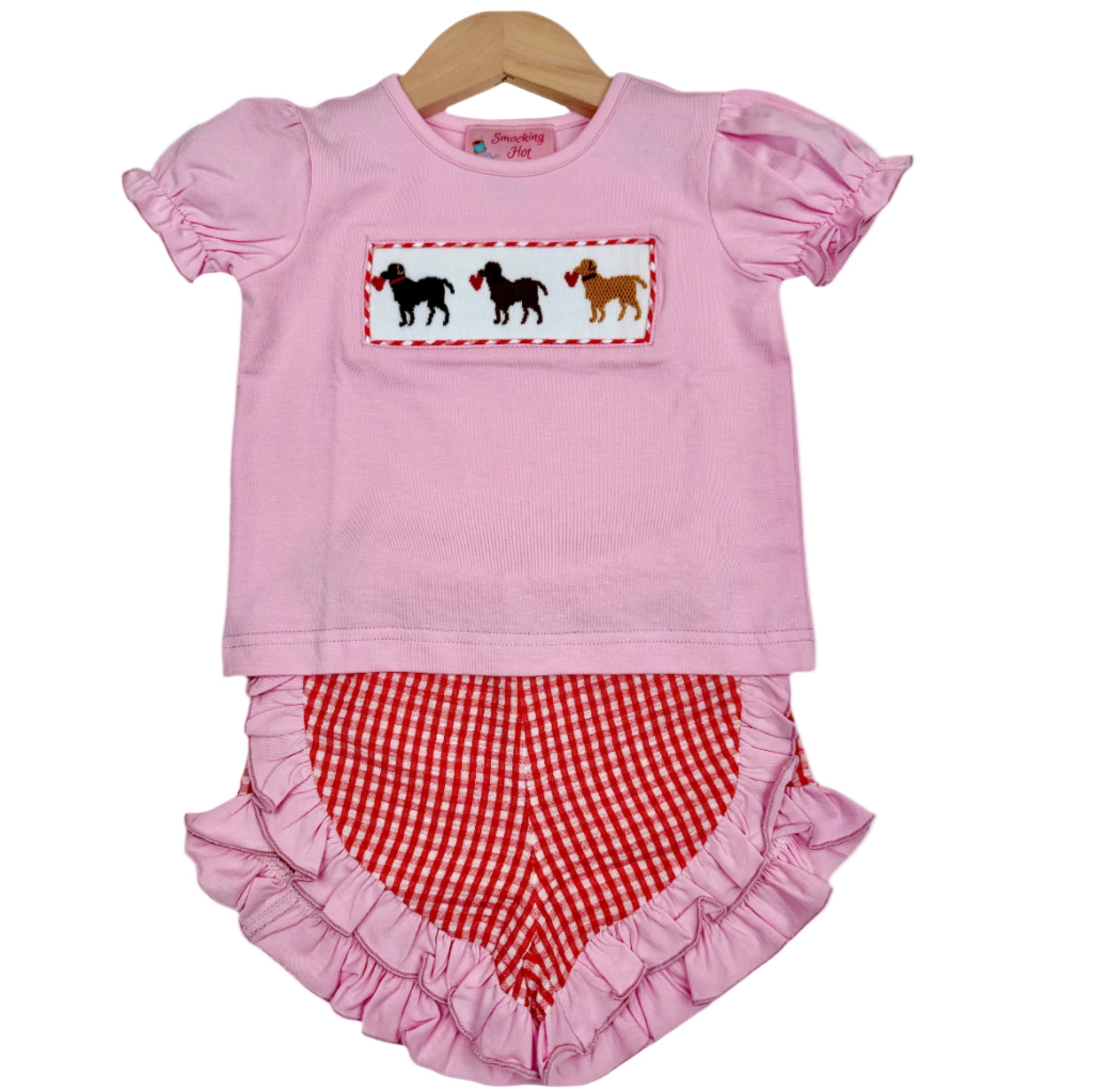 Girls pink hand smocked top with three Valentines puppy dogs and hearts, paired with red gingham ruffle bloomers.