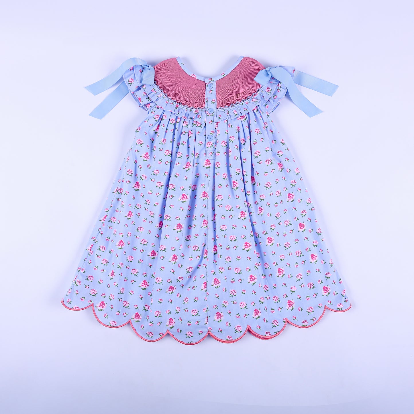 Full back view of girls light blue floral hand-smocked dress featuring back button closure and shoulder ribbons.