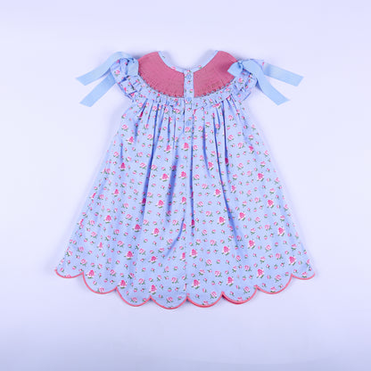Full back view of girls light blue floral hand-smocked dress featuring back button closure and shoulder ribbons.