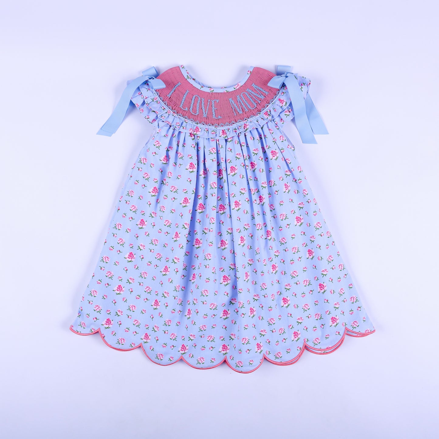 Girls light blue floral hand-smocked dress with I Love Mom embroidery, shoulder bows, and scalloped hem front view.