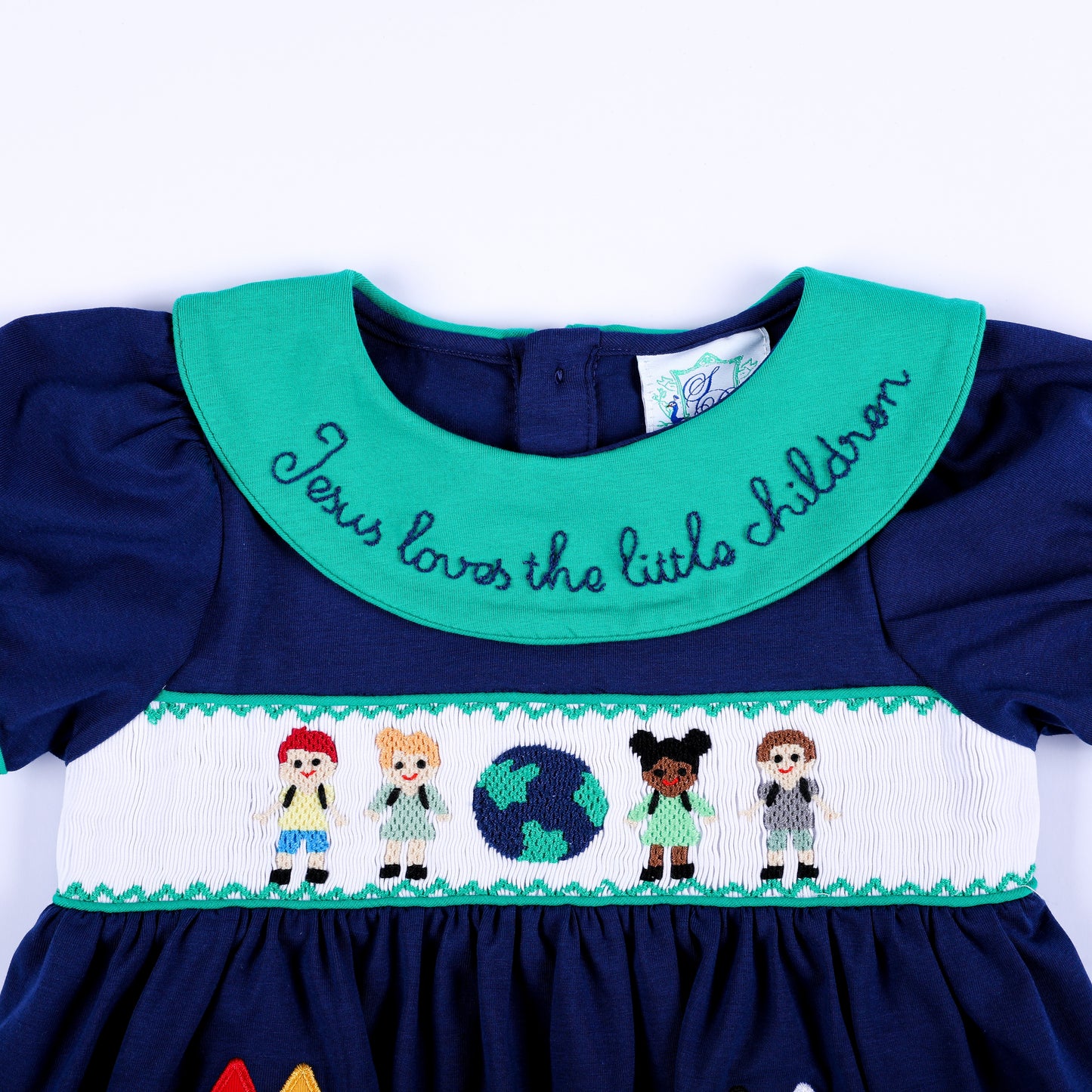 Front detail of embroidered green collar and hand smocked chest panel with kids and globe on navy top.