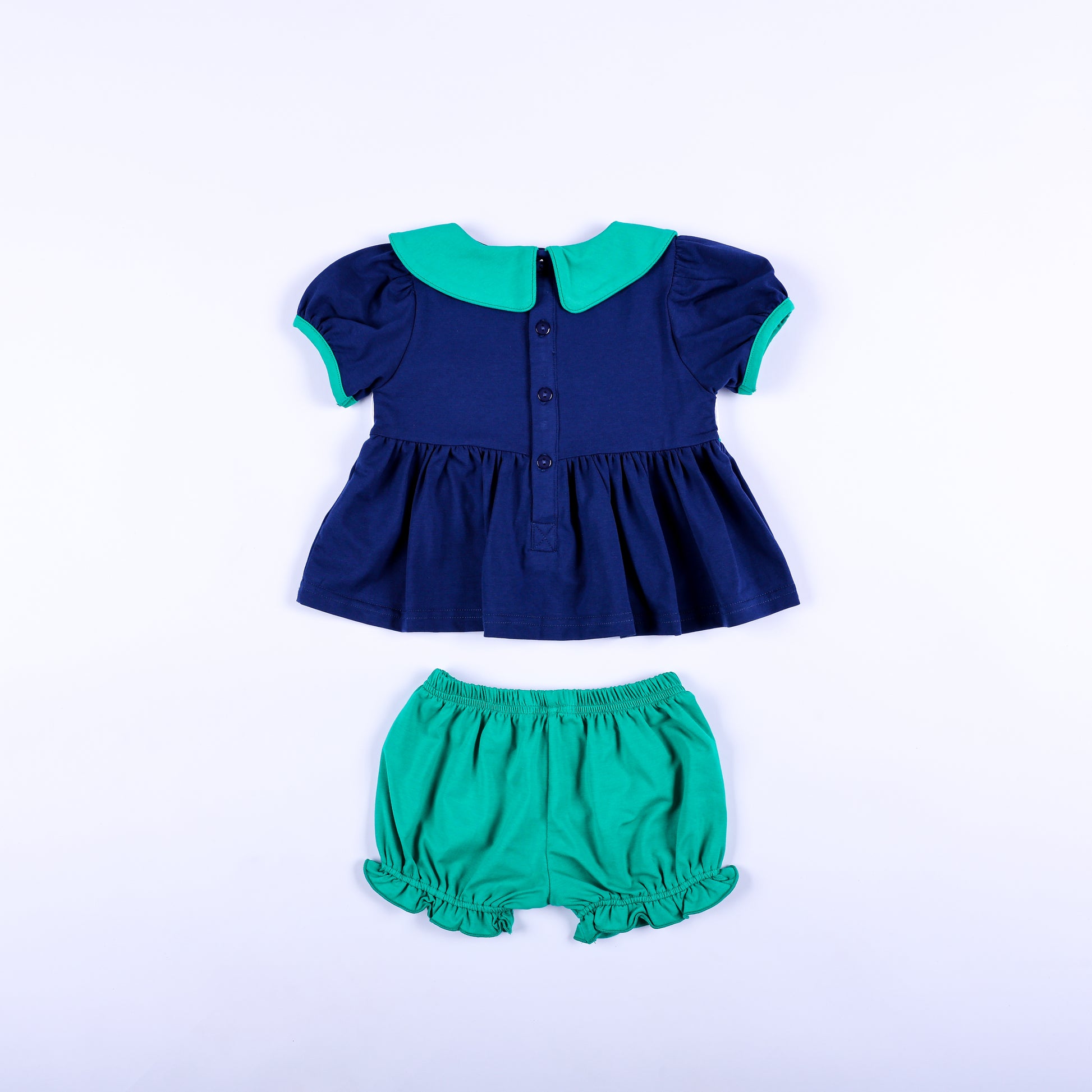 Full back view of Jesus Loves the Little Children navy smocked top with buttons and green bloomer shorts.