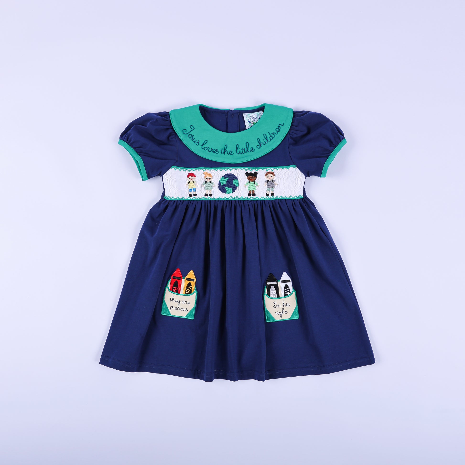 Navy hand-smocked dress with a 'Jesus Loves the Little Children' green embroidered collar and sweet crayon pockets.