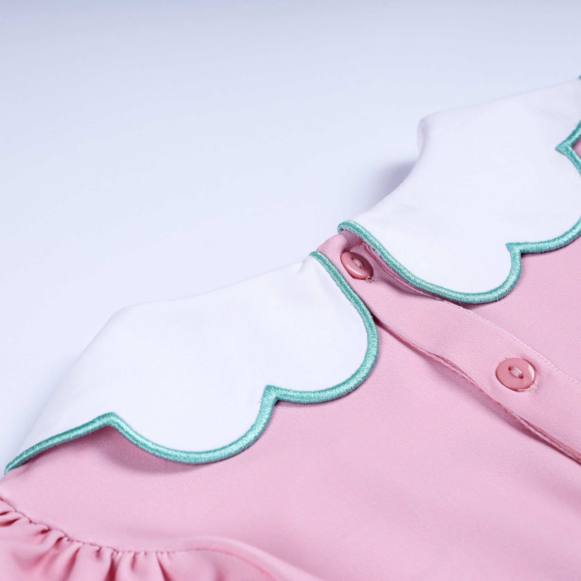 Back collar detail showing pink button closure on white scalloped Peter Pan collar with turquoise trim.