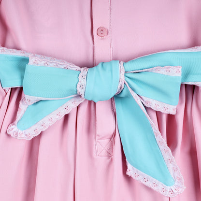 Close-up of turquoise fabric sash bow with delicate white lace trim on back of pink smocked baby dress.