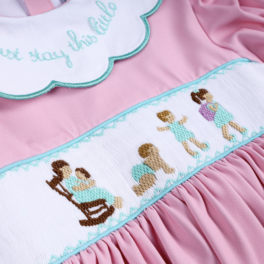 Intricate hand-smocked embroidery panel depicting mother and child growing up on pink bloomer dress top.