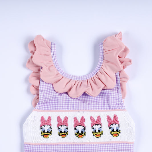 Close-up of girls purple gingham smocked swim top with pink ruffle collar and hand-embroidered ducks.