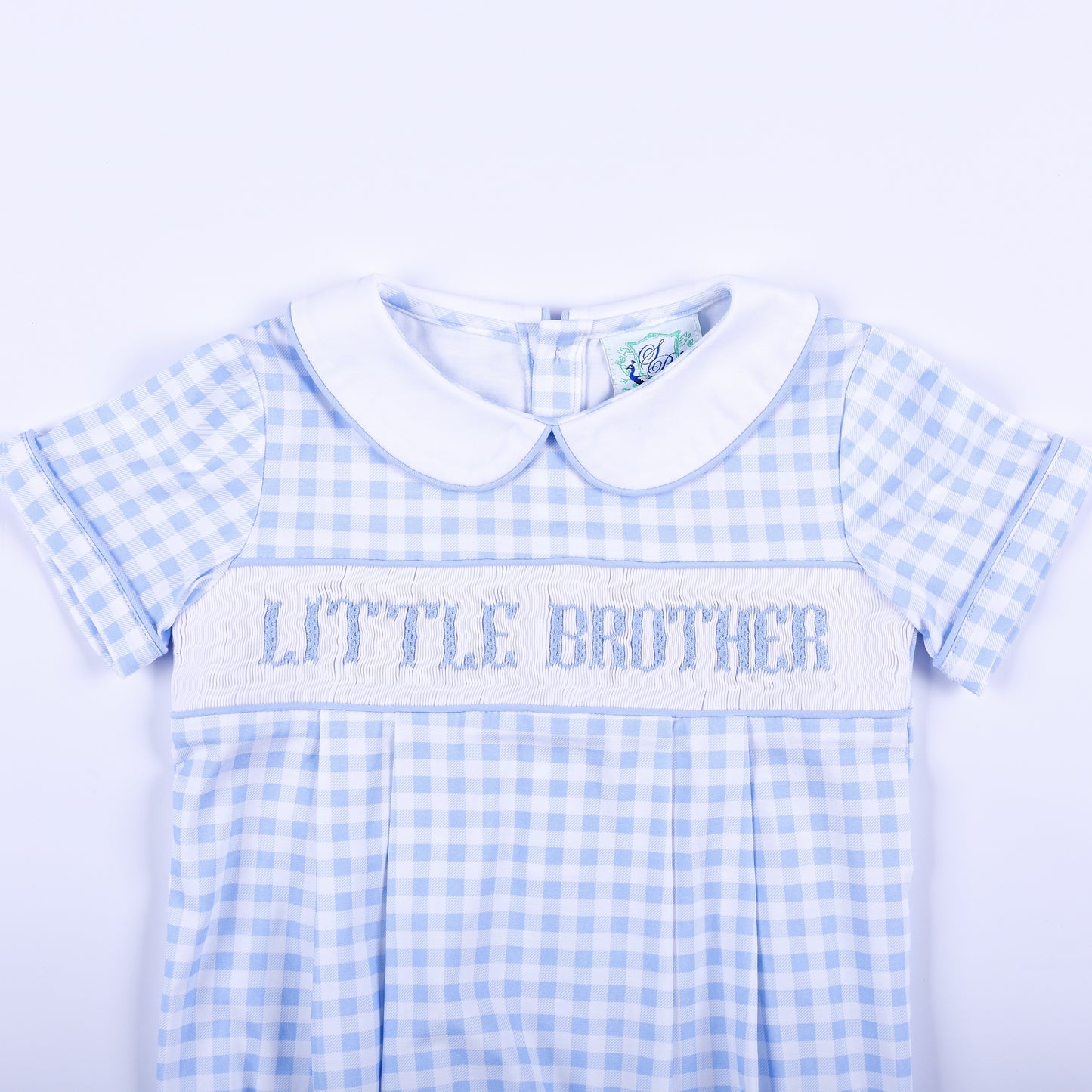 Detailed view of hand-smocked Little Brother embroidery on a light blue gingham baby boy bubble outfit.