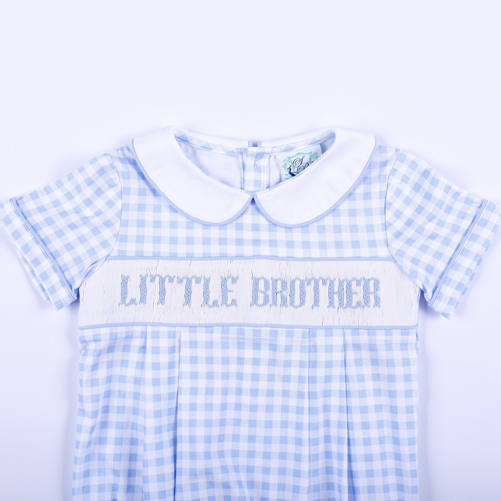Detailed view of hand-smocked Little Brother embroidery on a light blue gingham baby boy bubble outfit.