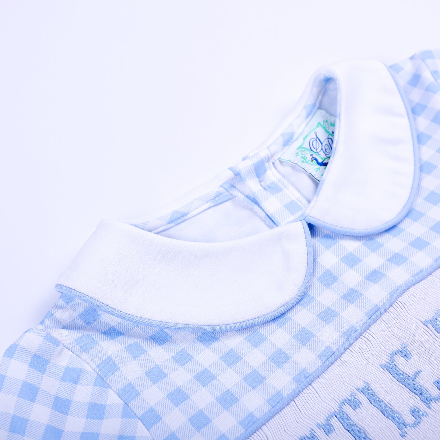 Close-up of the classic white Peter Pan collar on a light blue gingham smocked Little Brother baby bubble.