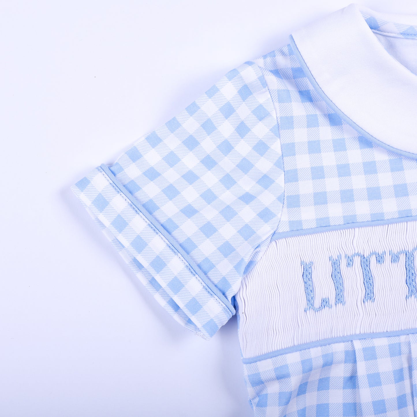Close-up of the piped short sleeve and detailed smocked chest on a blue gingham Little Brother bubble.