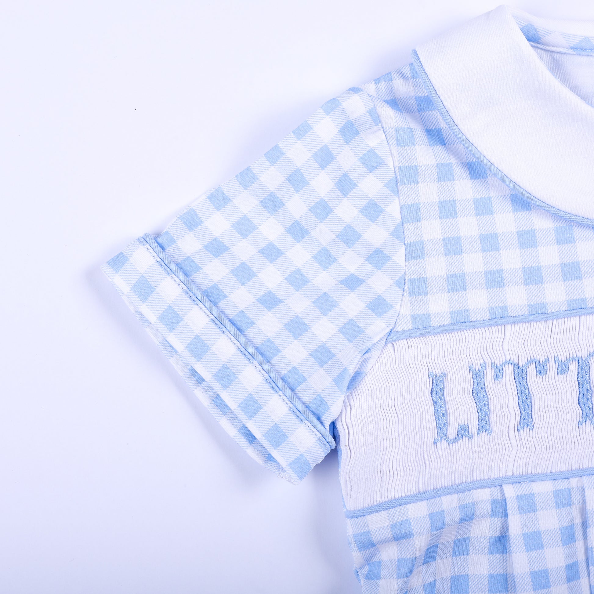 Close-up of the piped short sleeve and detailed smocked chest on a blue gingham Little Brother bubble.