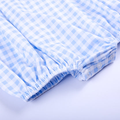 Detailed view of elasticized leg openings with bottom snap closures on blue gingham baby bubble romper.