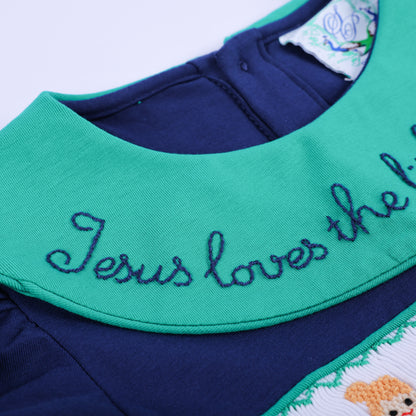 An extreme close-up of the navy smocked dress, highlighting the vibrant green hand-embroidered collar text detail.