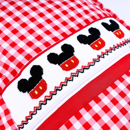 Close-up detail of hand-embroidered Mickey Mouse smocked band on red gingham boys full-size backpack.