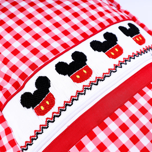 Close-up detail of hand-embroidered Mickey Mouse smocked band on red gingham boys full-size backpack.