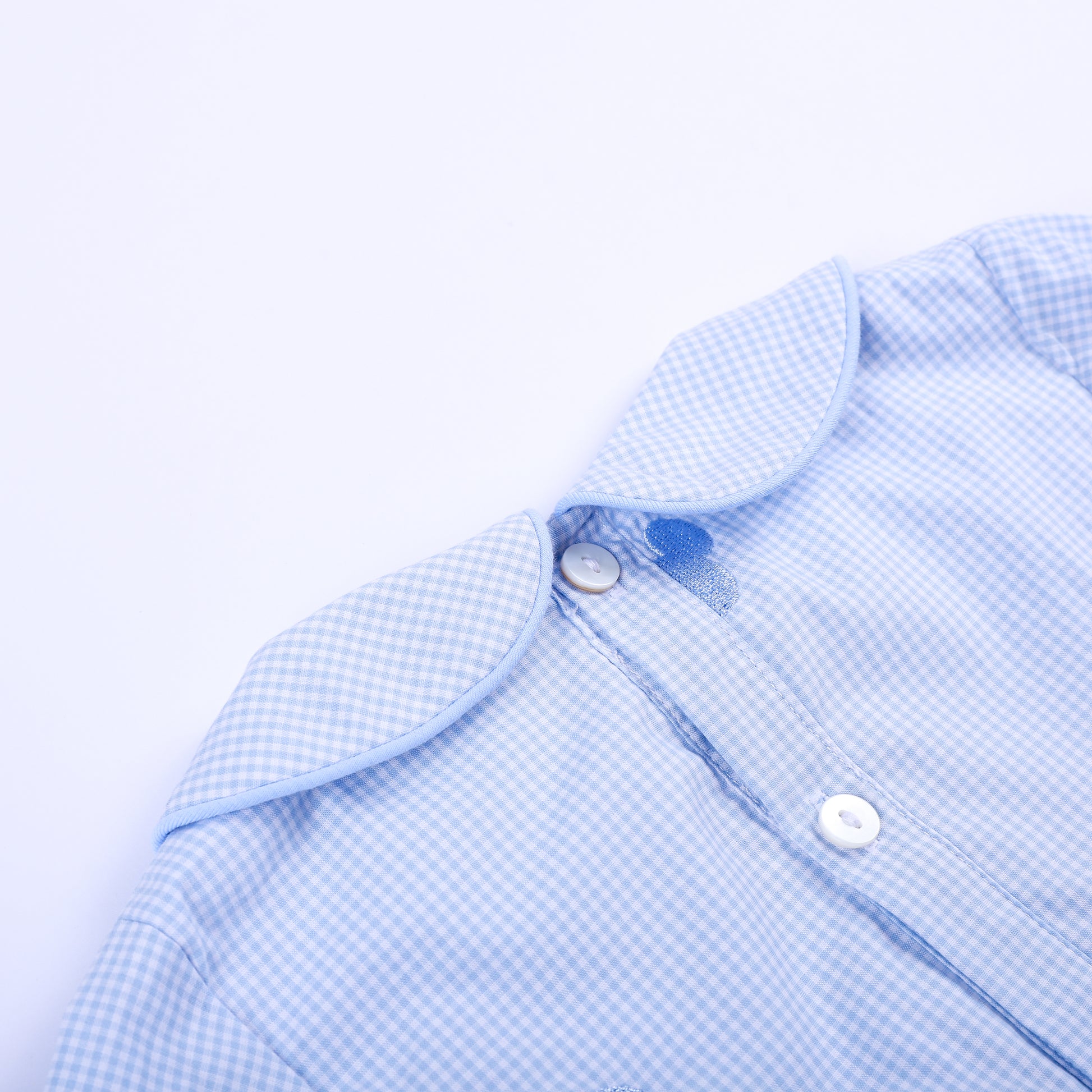 Close-up back collar view showing secure button closure and fine gingham pattern on Oh Twodles smocked boys bubble.