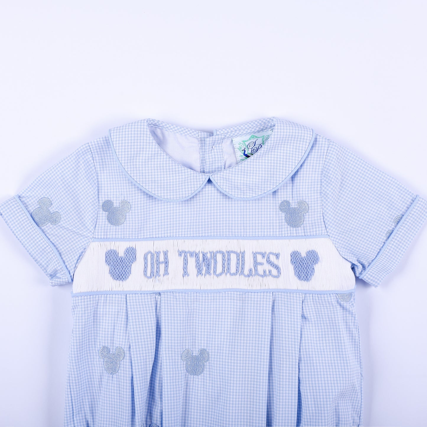 Close-up front view of Oh Twodles hand smocked boys bubble showing Peter Pan collar and hand embroidered chest band.