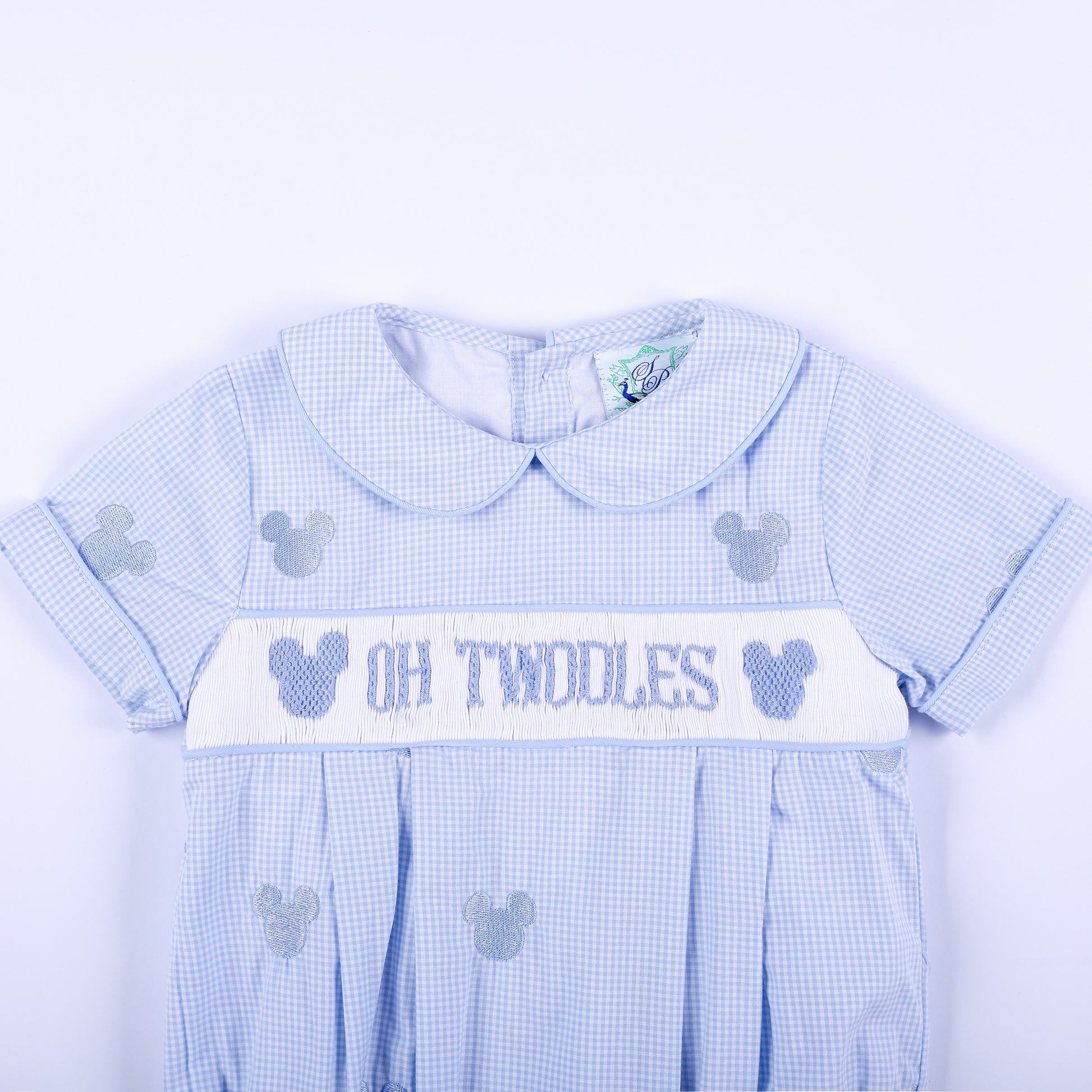 Close-up front view of Oh Twodles hand smocked boys bubble showing Peter Pan collar and hand embroidered chest band.