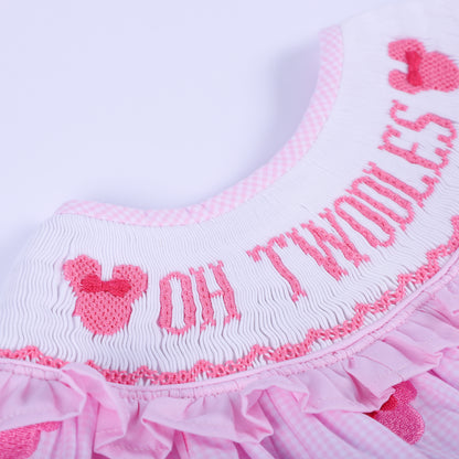 Macro detail of Oh Twoodles hand embroidered text on smocked ruffled neck collar of pink gingham baby outfit.