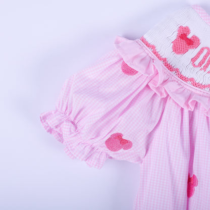 Close-up shot of pink gingham flutter sleeve with ruffled cuff and hand embroidered mouse head on baby bubble.