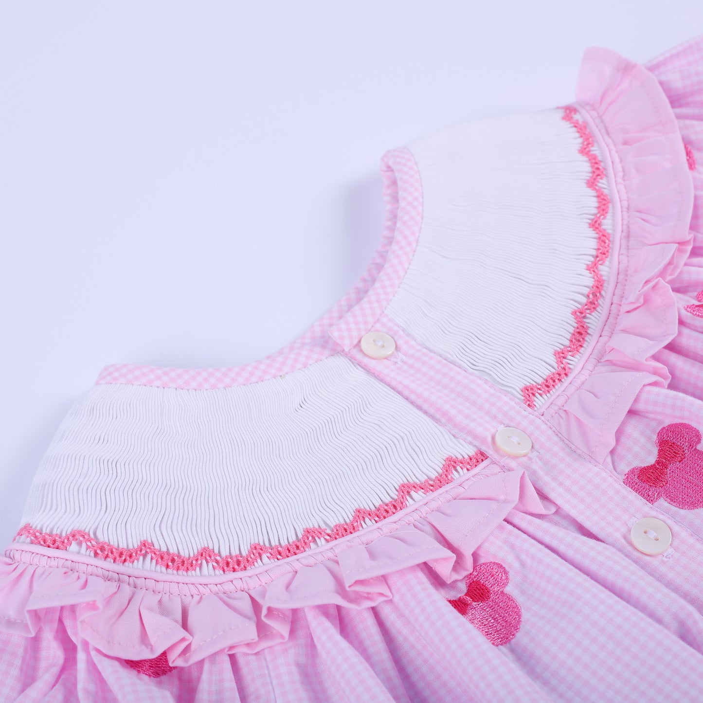 Close-up of back button closure detail on pink gingham Oh Twoodles hand smocked baby girl birthday bubble romper.