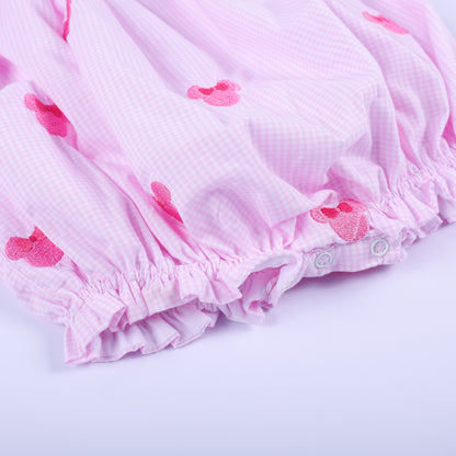 Close-up of bottom snap closure and elastic ruffled hem on pink gingham Oh Twoodles hand smocked bubble romper.