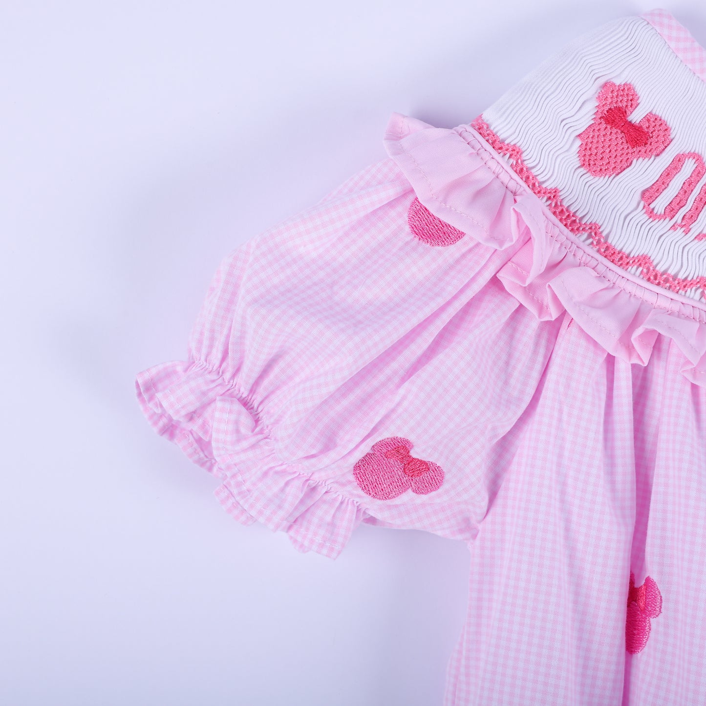 Detailed view of flutter ruffled sleeve on pink gingham smocked baby bubble with hand embroidered mouse accent.